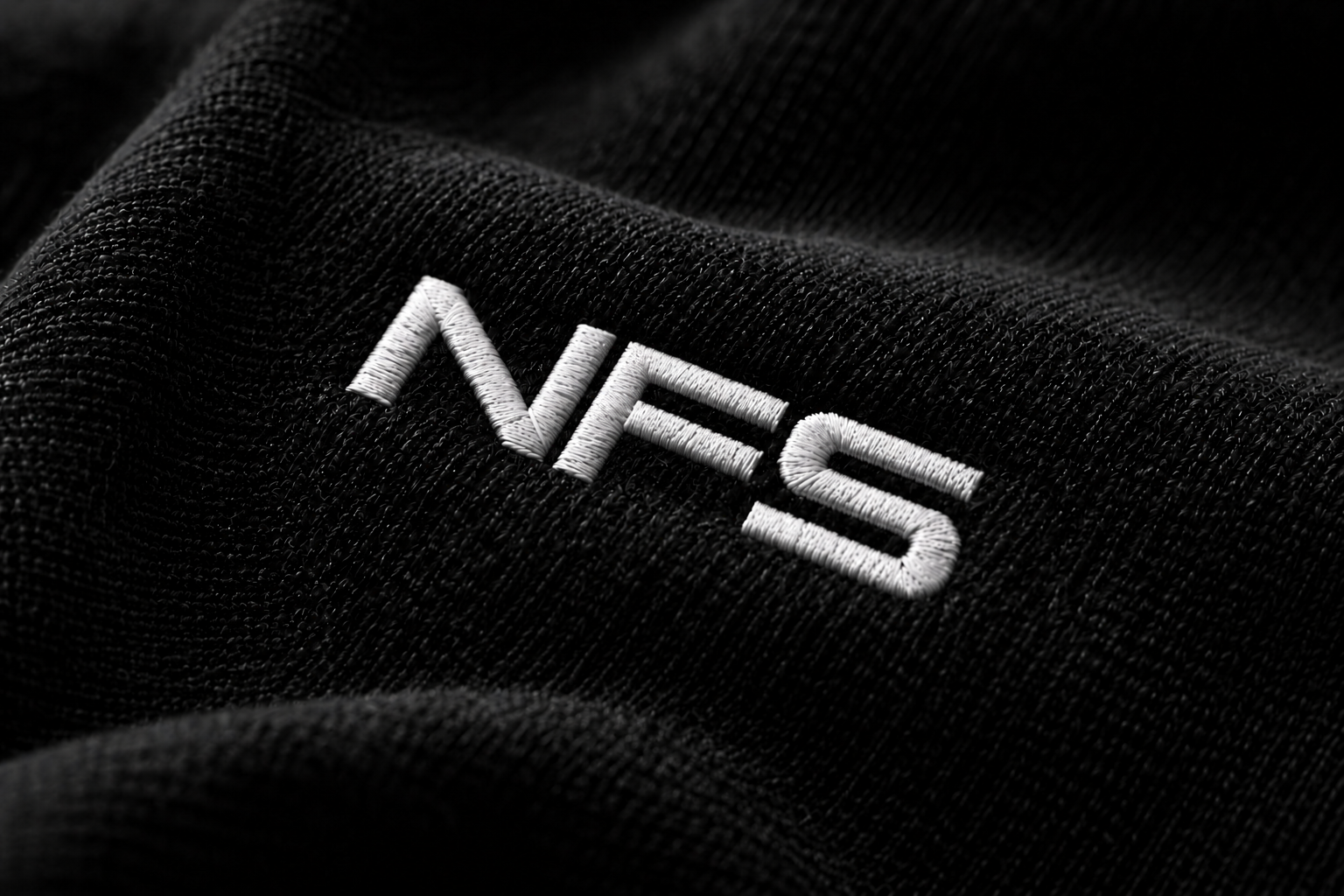 Siyah kumaş üzerindeki beyaz NFS nakışının yakın planı